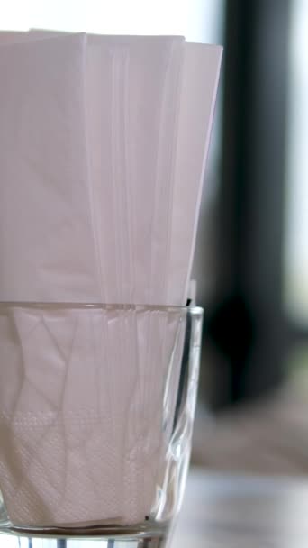 Gros plan Vidéo de stock de 4k de mouchoirs en papier blanc dans une boîte en métal debout sur la table à l'extérieur dans un restaurant ensoleillé de la rue. La main d'une femme prend une serviette de papier soufflant par le vent. Images 4k - Séquence, vidéo