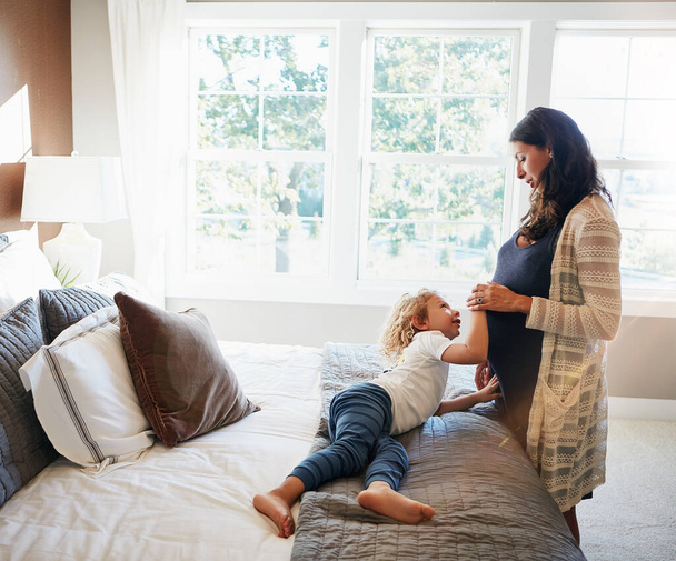 Onnellinen perheen makuuhuone, nainen raskaus tai lapsi kosketa vatsaa tarkistaa sikiön, liikkuva vatsa tai synnytystä vatsa. Nuorten lapsi, raskaana oleva äiti ja utelias vauvan hedelmällisyyden kehittämiseen asunnossa sängyssä. - Valokuva, kuva