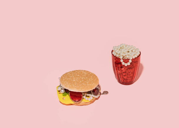 Hamburguesa de joyería creativa con soda. Concepto de comida rápida. Fondo rosa pastel.  - Foto, imagen