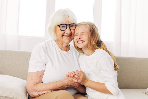 Woman sofa granddaughter girl mother couch generation love old sitting happy senior child grandmother home elderly hug lifestyle daughter family - Photo, Image
