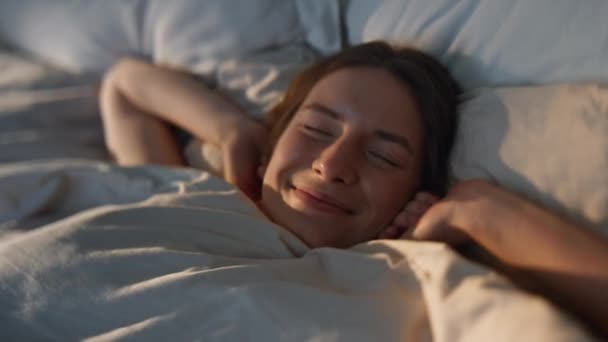 Boldog nő nyújtózkodó ágy napfény közelkép. Gondtalan mosolygós lány, aki puha, kényelmes lepedőn ébred. Az örömteli, gyönyörű nők élvezik az energiával teli napot. Pozitív érzelmek boldogság - Felvétel, videó