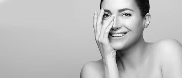 Radiant woman with natural beauty, flawless skincare and smiling face, monochrome portrait, indoor setting. Panorama banner with lateral copyspace. - Photo, Image