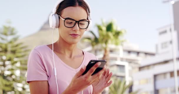 Music, headphones and woman with phone in city in summer for podcast outdoor. Radio, smartphone and happy person dance in urban town, listen to audio or hearing sound, mobile app media or technology. - Footage, Video