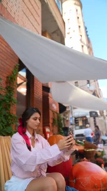 Krásná mladá žena v růžovém, držící smartphone, na farmářském trhu. Vysoce kvalitní 4K záběry - Záběry, video