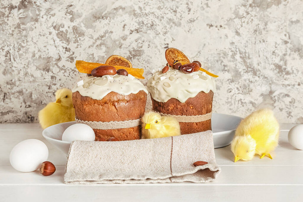 Pastel de Pascua con figuras de pollo y huevos en mesa de madera blanca cerca de la pared de grunge beige - Foto, imagen