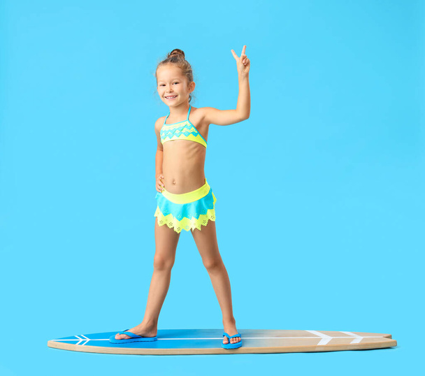 Little girl with surfboard on blue background - Photo, Image