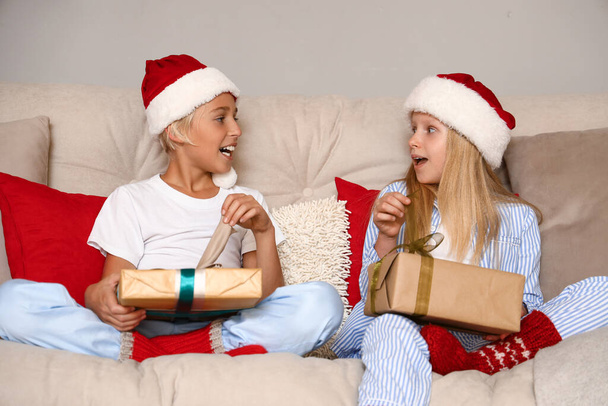 Niños pequeños con regalos sentados en casa en Nochebuena - Foto, Imagen