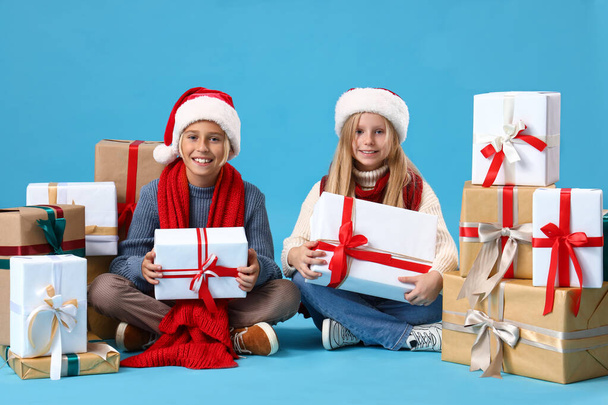 Маленькие дети с рождественскими подарками сидят на синем фоне - Фото, изображение