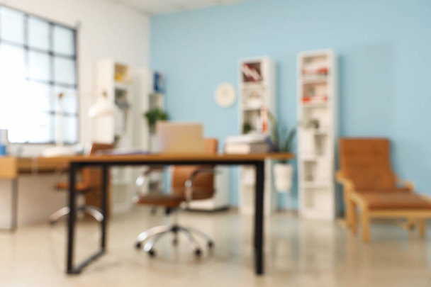 Wazig zicht op stijlvol kantoor met werkplekken en legplanken - Foto, afbeelding