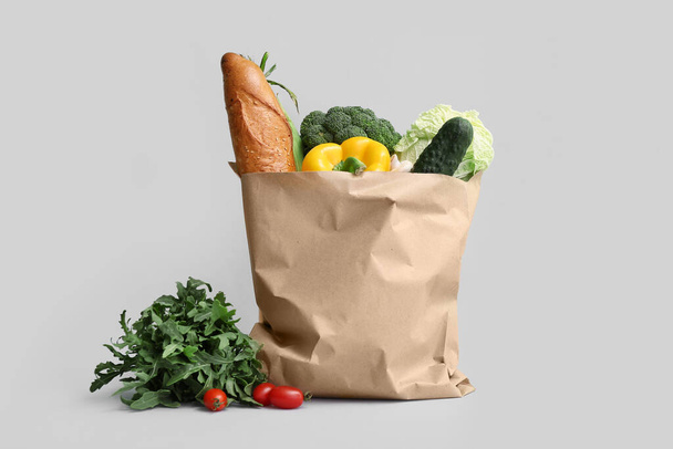 Bolsa de compras de papel con verduras frescas sobre fondo gris - Foto, Imagen