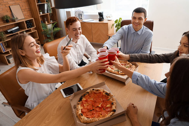 Grupa młodych kolegów pijących pizzę na imprezie biurowej - Zdjęcie, obraz
