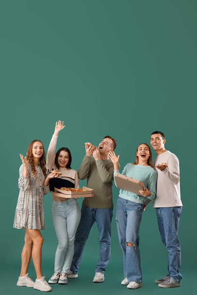 Grupo de jóvenes amigos con sabrosa pizza sobre fondo verde - Foto, imagen