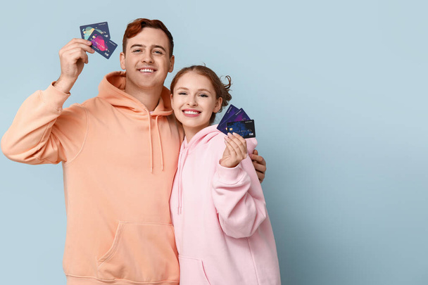 Junges Paar mit Kreditkarten auf blauem Hintergrund - Foto, Bild