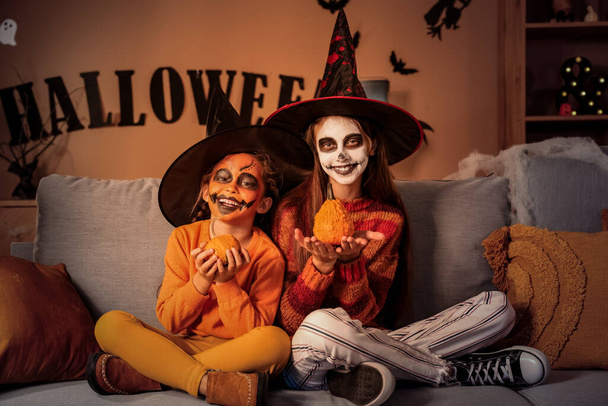 Dívky oblečené na Halloween s dýněmi doma ve večerních hodinách - Fotografie, Obrázek