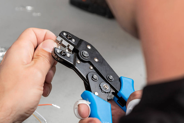 Αρσενικός μηχανικός επεξεργάζεται καλώδια. Η διαδικασία εργασίας ενός ηλεκτρολόγου στο χώρο εργασίας. μόνωση σύρματος καθαρισμού από κοντά τα χέρια ηλεκτρολόγου - Φωτογραφία, εικόνα