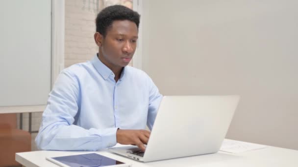 Hustender afrikanischer Geschäftsmann mit Laptop im Büro - Filmmaterial, Video