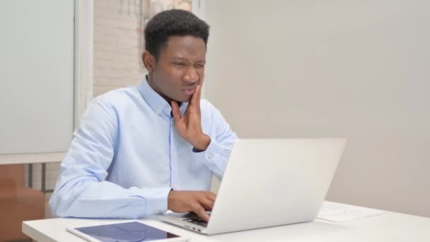African Businessman z bólem zęba Praca na laptopie w biurze - Materiał filmowy, wideo