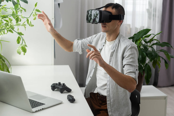 Jonge man met baard draagt een virtual reality bril in een moderne interieurcoworking studio. Smartphone met VR-bril op de headset. Horizontaal, flares effect, - Foto, afbeelding
