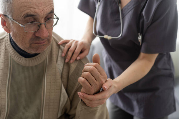 Медсестра держит за руку пожилого человека в доме престарелых
 - Фото, изображение