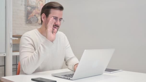 Hombre de mediana edad haciendo chat de vídeo en el ordenador portátil en la oficina - Metraje, vídeo