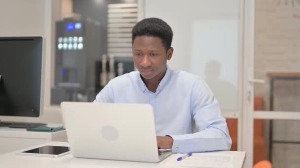 Afrikaanse zakenman glimlachend bij de camera tijdens het werken op Laptop in Office - Video