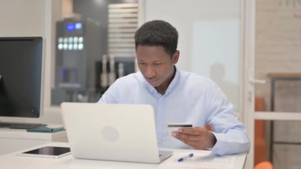 Empresario africano disfrutando de compras en línea en el ordenador portátil - Metraje, vídeo