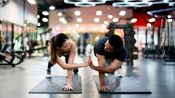 Sportler und Sportlerin machen gemeinsam Liegestütze im Fitnessstudio: Kraft, Einheit und Motivation - Foto, Bild