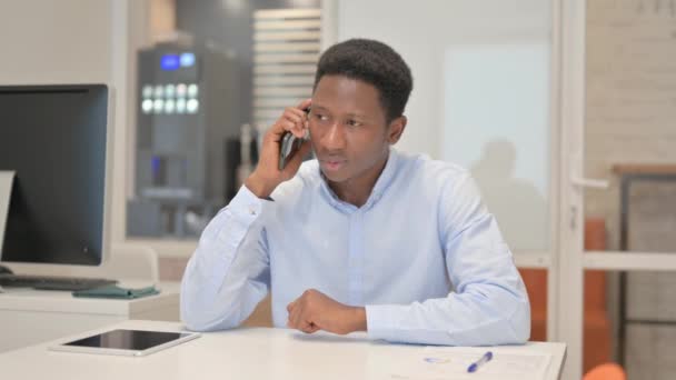 Uomo d'affari africano che parla al telefono in ufficio - Filmati, video