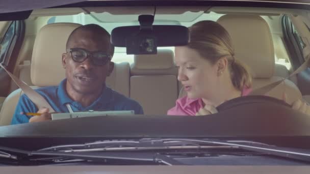 Mediana toma de profesor de autoescuela explicando los resultados del examen de conducir a la mujer mientras está sentado dentro del coche - Imágenes, Vídeo