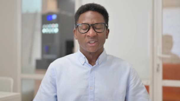 Portret afrykańskiego biznesmena z bólem głowy w biurze - Materiał filmowy, wideo