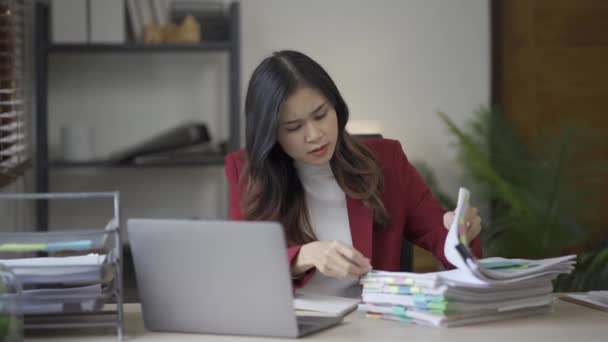 Стрессовая азиатская бизнесвумен в костюме переживает из-за финансовых проблем, связанных с завершением бумажной работы в офисе Женщина разочарована работой с документами на столе - Кадры, видео