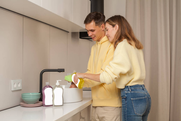 Happy couple laver la vaisselle avec du liquide vaisselle avec étiquette vierge - Photo, image