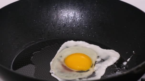 Primo piano di un uovo che frigge in una pentola, colpito al rallentatore. Concetto cucina. - Filmati, video