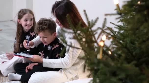 Kleine Kinder mit ihrer Familie neben dem Weihnachtsbaum. Familienwerte. Konzept der Weihnachtsferien. - Filmmaterial, Video
