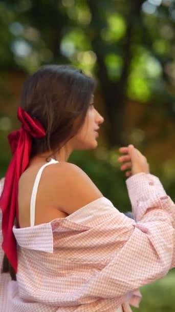 Két élénk fiatal hölgy animációs beszélgetést folytat a parkban. Kiváló minőségű 4k felvételek - Felvétel, videó