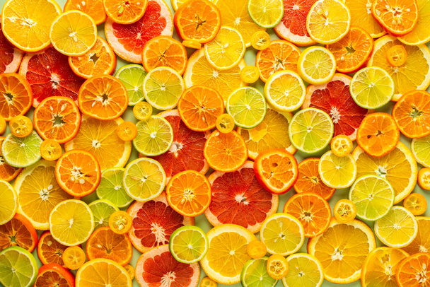 Arrière-plan d'agrumes mûrs, tranches d'orange et de mandarine, citron vert, kumquat et tranches de pamplemousse, préparation pour la célébration de Noël - Photo, image
