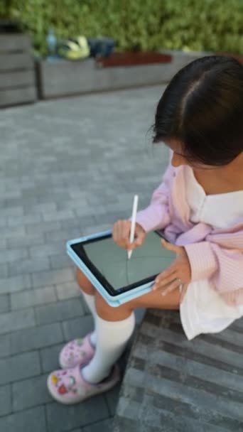 Una hermosa joven que trabaja con una tableta en un día de verano al aire libre. Imágenes de alta calidad 4k - Imágenes, Vídeo