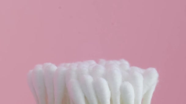 Katoen wattenstaafjes van witte kleur draaien in een cirkel op een roze achtergrond. - Video