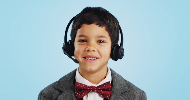 Face, studio or child consultant in call center talking or networking for telecom on blue background. Young, contact or friendly kid sales agent in communication or conversation at customer service. - Photo, image