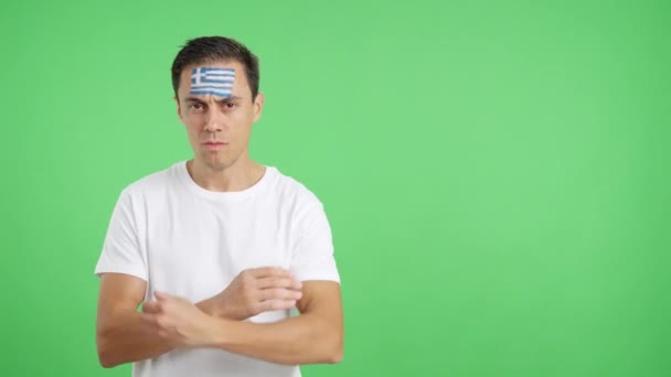 Βίντεο στο στούντιο με το χρώμα ενός αξιοπρεπούς και σοβαρού άνδρα με ελληνική σημαία ζωγραφισμένη στο πρόσωπο κοιτάζοντας την κάμερα με αξιοπρέπεια - Πλάνα, βίντεο