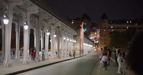 Frankrijk, Parijs, 01 augustus 2023: Mensen lopen 's nachts over een verlichte voetgangersbrug Parijs Frankrijk. - Video