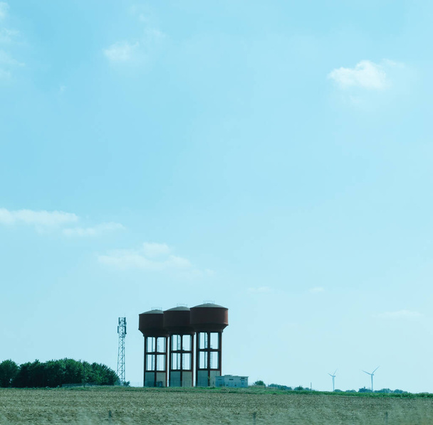 Torri idriche costruite in modo sicuro in un ambiente rurale francese, incorniciato da un vivido cielo blu, che difende pratiche ecosostenibili. - Foto, immagini