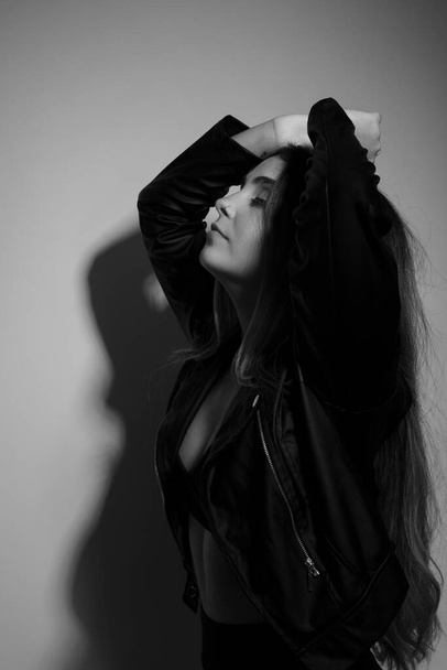Hermosa joven modelo, con la mano en la cabeza haciendo poses para la foto. Retrato en blanco y negro en el estudio - Foto, Imagen