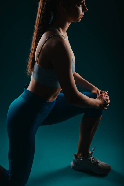 自信を持って女性のフィットネスインストラクター ダークスタジオで強力なトレーニング筋肉 - 写真・画像