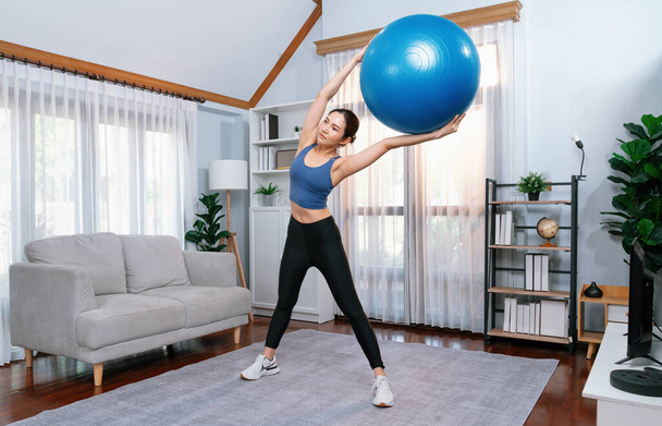 Nuori houkutteleva aasialainen nainen urheiluvaatteet ote ja nosta istuvuus pallo kohdistaminen abs lihas tehokas energinen koti käyttää rutiinia. Voimakas - Valokuva, kuva