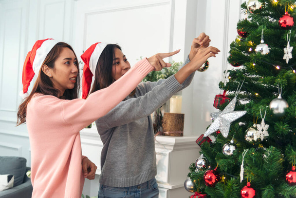 手を使って2人の女性の兄弟がクリスマスツリーの赤いボール,バブル,雪のフレークを飾ります. 赤いボールバブルを飾っている手を閉じます. アジアの女性の友人はバブルボールクリスマスツリーxmas休日を飾ります - 写真・画像