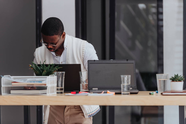 Черный мужчина делает бумажную работу и анализирует статистику в офисе. - Фото, изображение