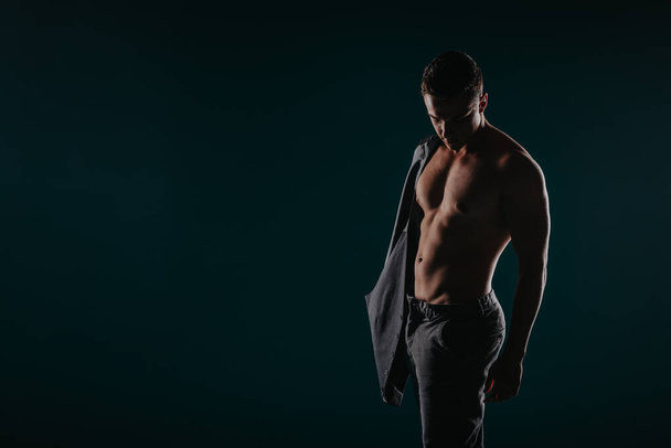 Γυμνασμένος άνθρωπος λυγίζει τους μυς, δείχνει ισχυρή σωματική διάπλαση. Κίνητρο για στόχους φυσικής κατάστασης. - Φωτογραφία, εικόνα