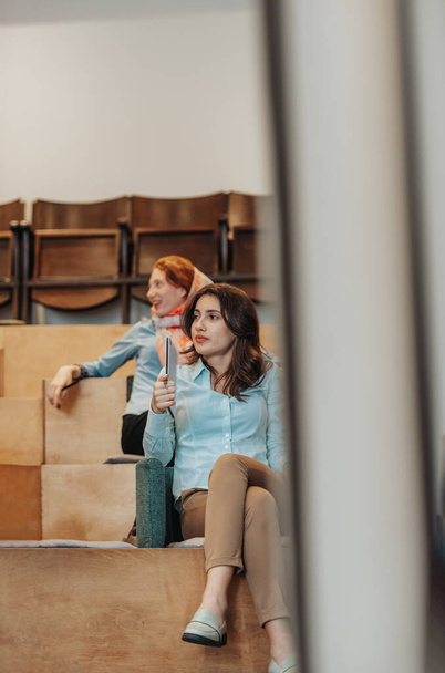 Фото работницы бизнеса, проходящей бизнес-тренинг на работе, сидящей в маленьком амфитеатре, держащей в руках ноутбук - Фото, изображение