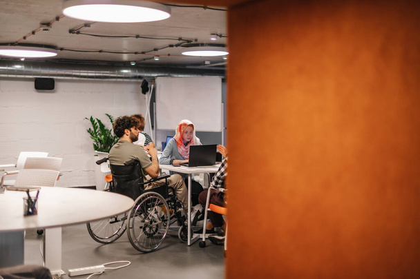 Équipe de travailleurs inclusifs ayant une séance de remue-méninges avec leur collègue handicapé au bureau - Photo, image